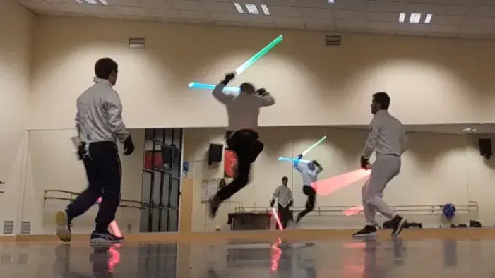 Jeune tireur et adulte en duel de sabre laser, lames vertes.